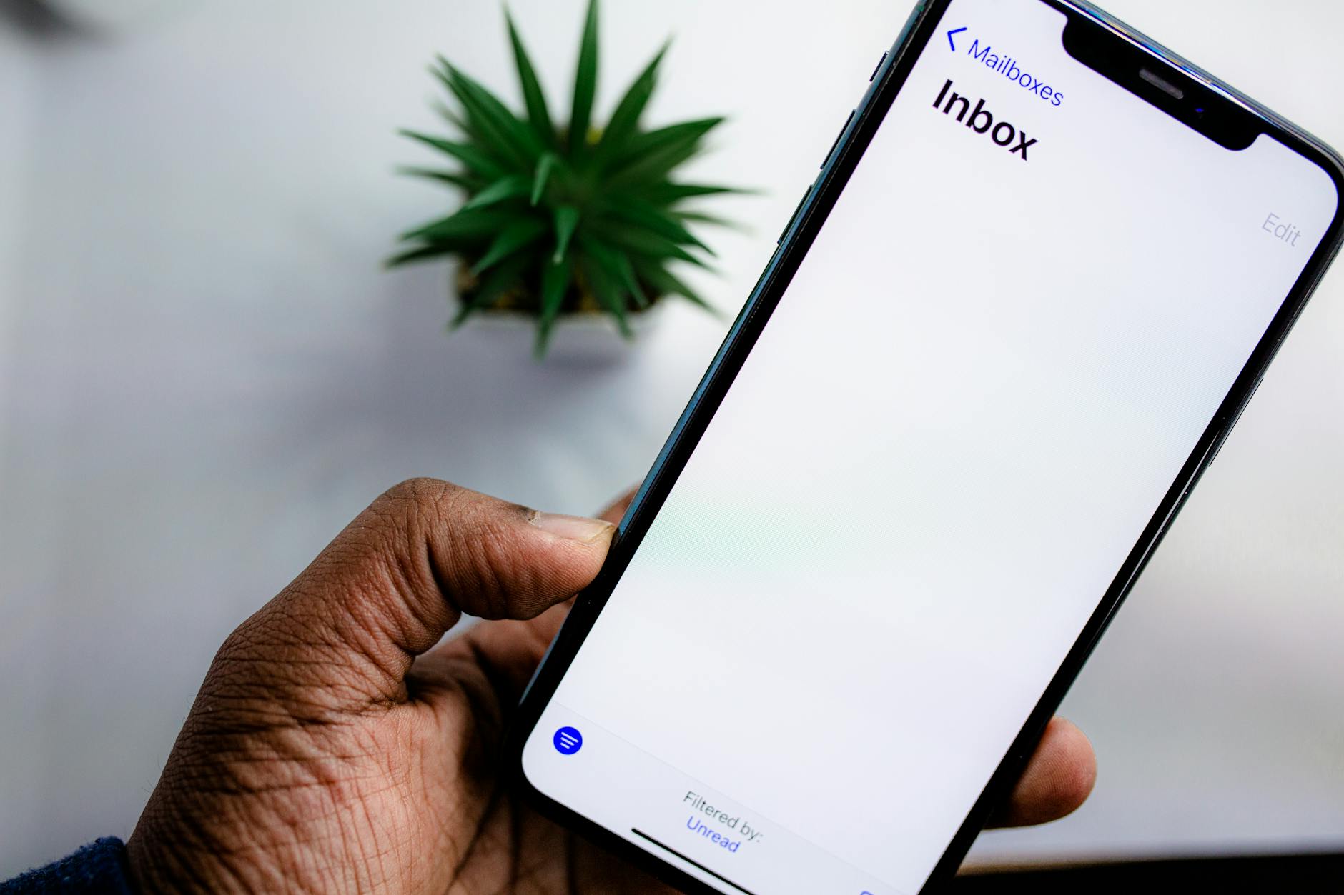 Dłoń dorosłej osoby trzyma smartfon z wyświetloną skrzynką e-mail