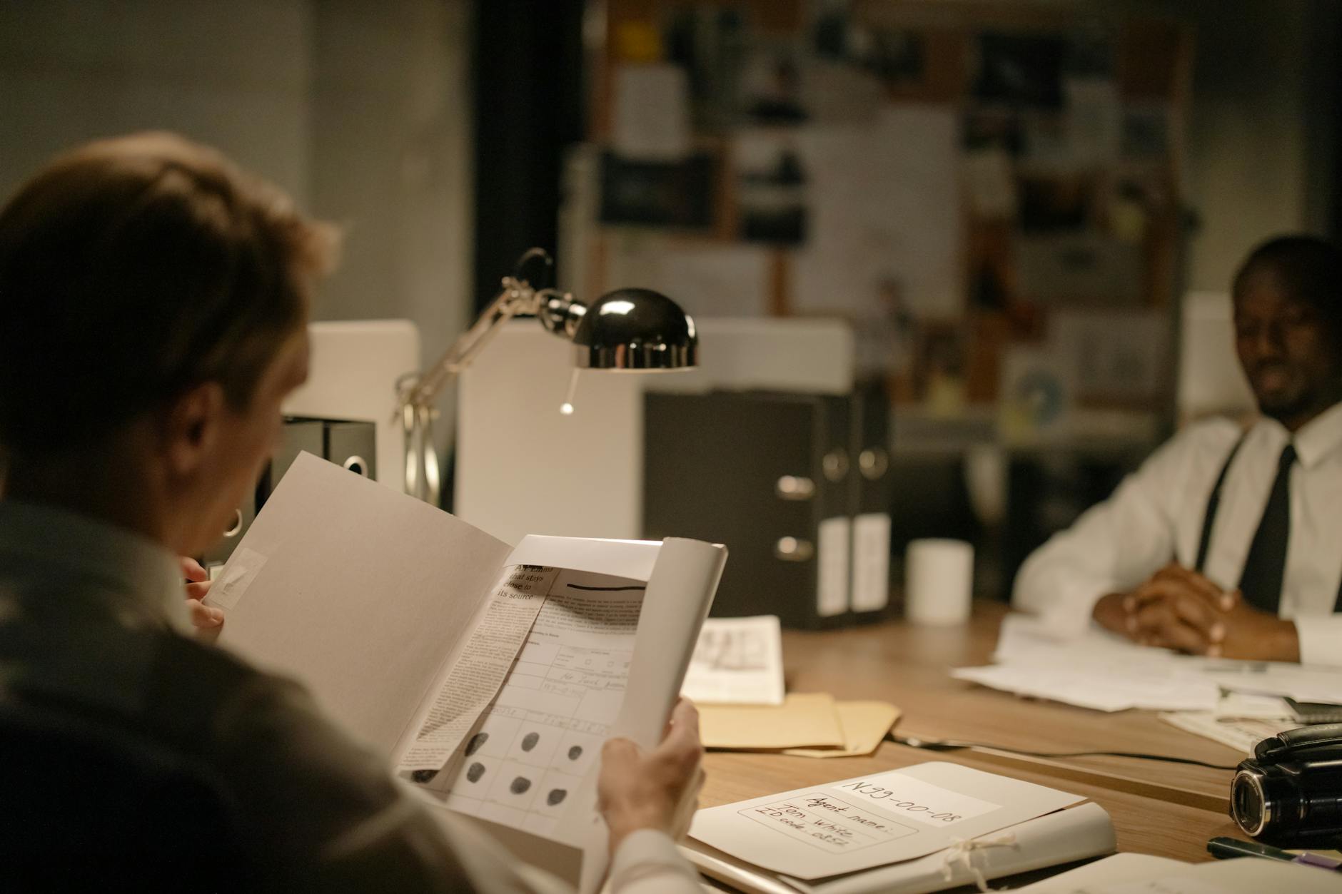 Śledczy analizują dokumenty w przyciemnionym biurze