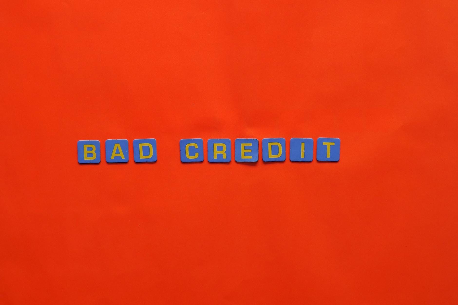 Niebieskie klocki z napisem Bad Credit na pomarańczowym tle