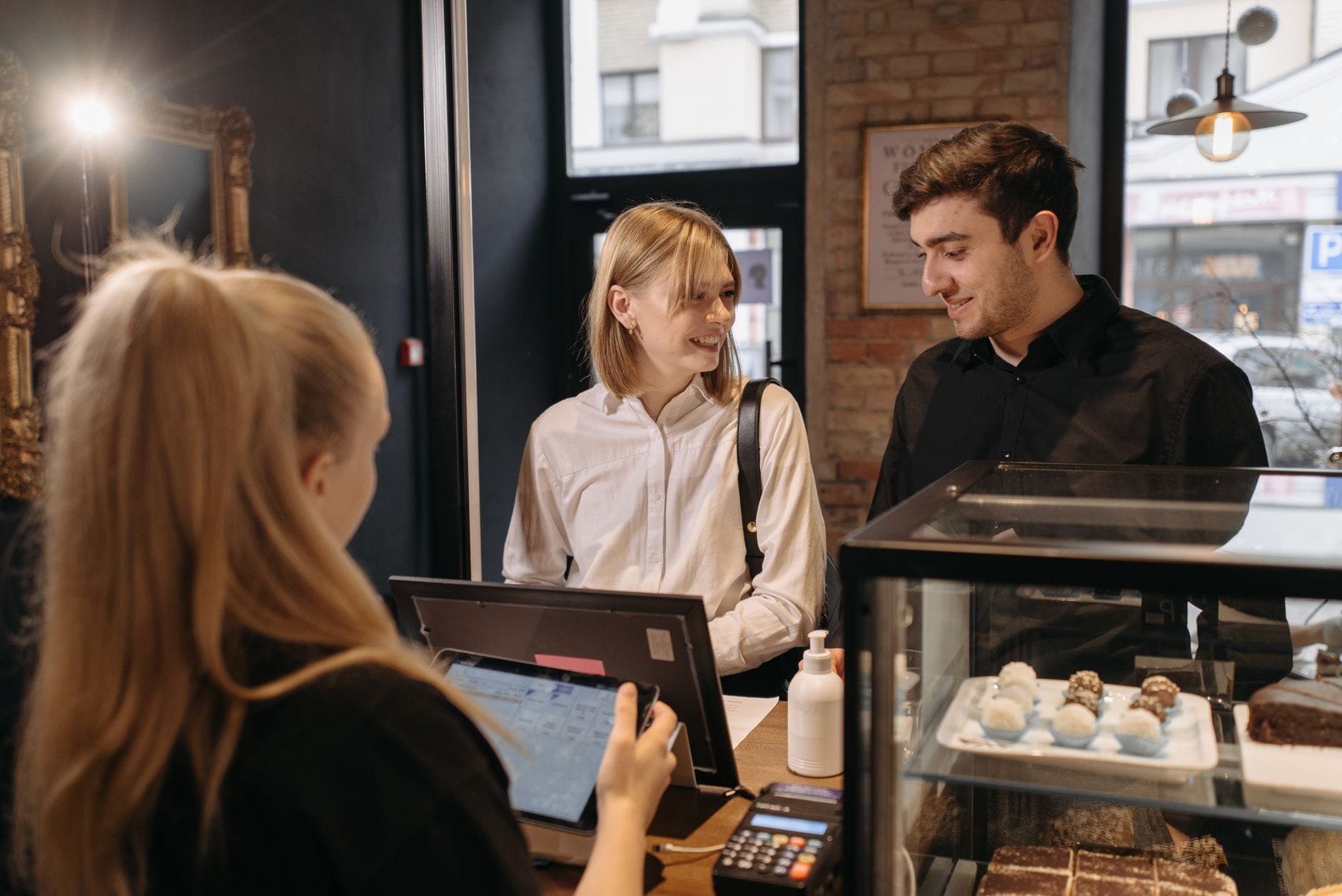 Klienci rozmawiają z baristą przy ladzie w przytulnej kawiarni
