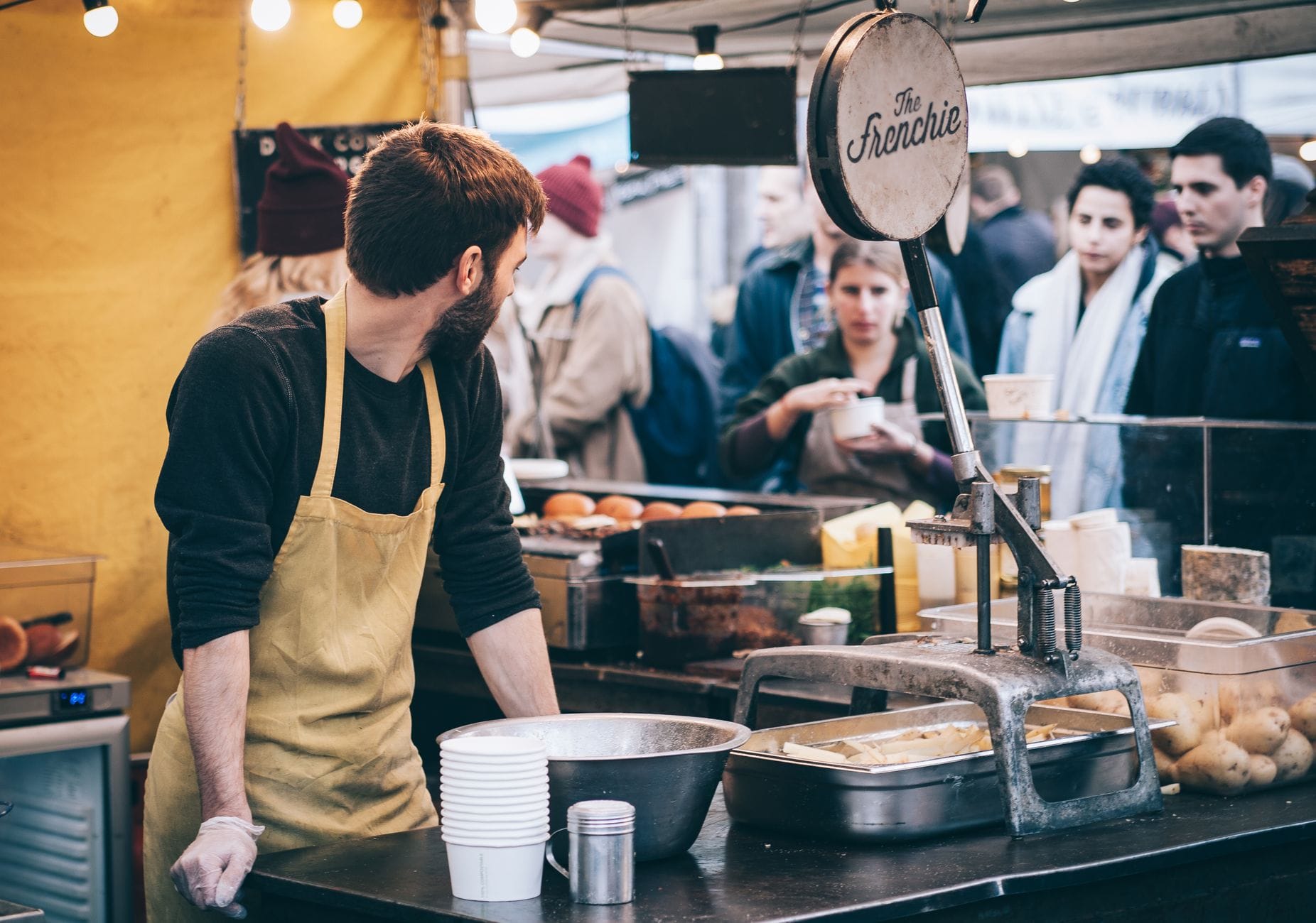Sprzedawca street foodu obsługuje klientów na zatłoczonym targu Sprzedawca street foodu obsługuje klientów na zatłoczonym targu